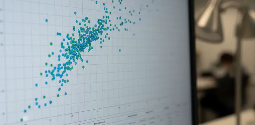 Monitor displaying a blue and green scatter plot, with a person seated behind